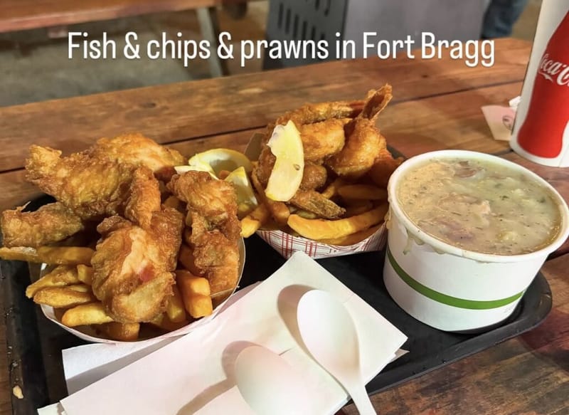 Basket of fried fish and basket of prawns with chips, a cup of chowder, and a Coca-Cola on a tray, text overlay reads Fish and chips and prawns in Fort Bragg