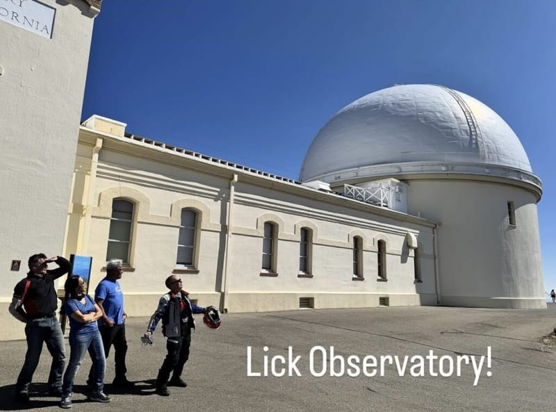 Four people looking up at the dome of Lick Observatory on a clear blue-sky day, building labeled University of California